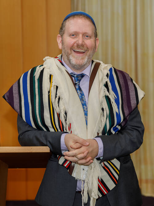 Image of a smiling Rabbi Finkelstein with hands clasped under his chin