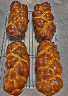 Image of six just baked challahs on a cooling rack