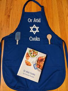 Image of blue "Or Atid Cooks"  apron and cookbook